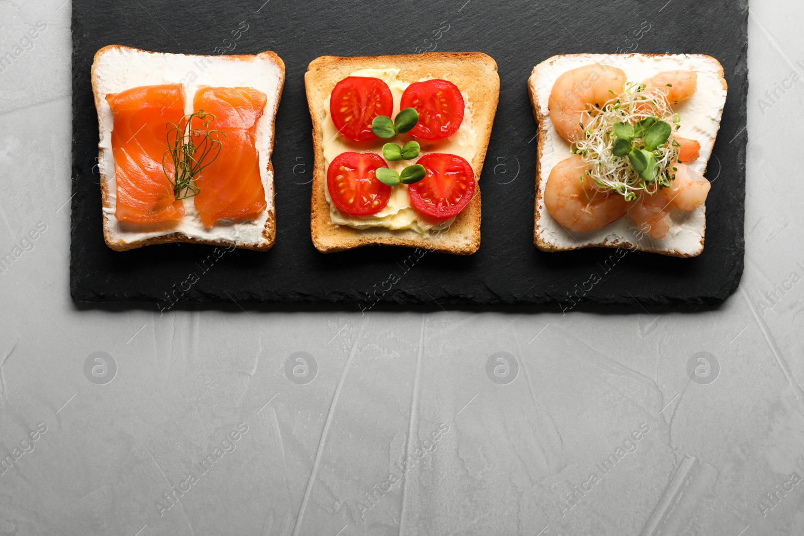 Photo of Different delicious toasts on light grey table, flat lay. Space for text