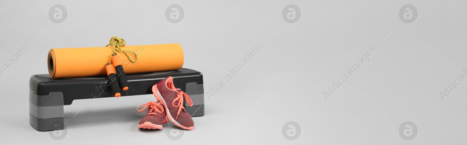 Image of Step platform, yoga mat, skipping rope and sneakers on light background, space for text. Banner design