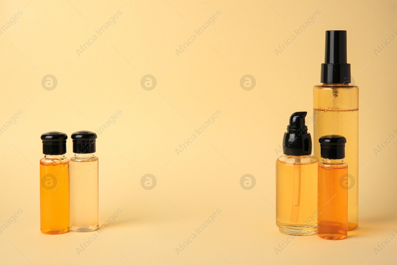 Photo of Many bottles of cosmetic products on beige background. Space for text