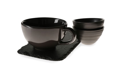 Photo of Set of black ceramic tableware with slate plate on white background