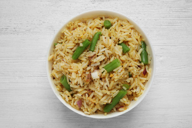 Photo of Tasty rice pilaf with vegetables on white wooden table, top view