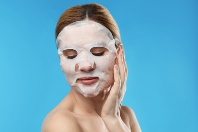 Photo of Beautiful woman with cotton mask sheet on face against color background