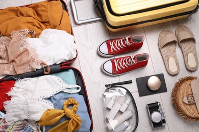 Photo of Suitcases with summer clothes, accessories and shoes on floor, flat lay