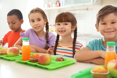 Photo of Children sitting at table and eating healthy food during break at school