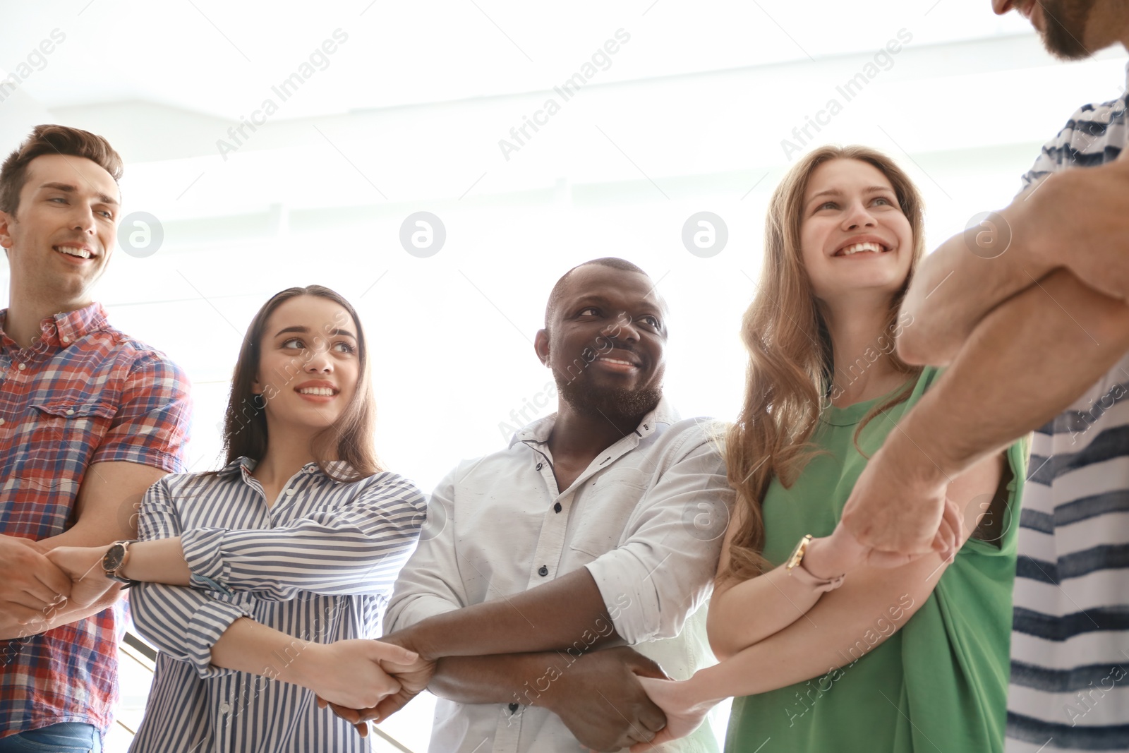 Photo of People holding hands on light background. Unity concept