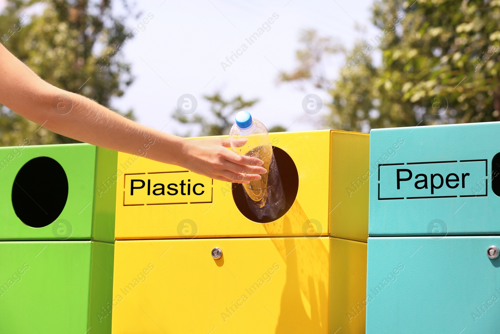 Photo of Woman throwing plastic bottle into sorting bin on city street, closeup. Recycling waste