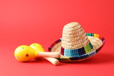 Photo of Mexican sombrero hat and maracas on red background