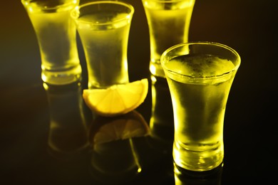 Shot glasses of vodka with lemon slice on dark background, space for text