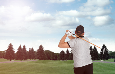 Image of Senior man playing golf on course with green grass, back view. Space for design