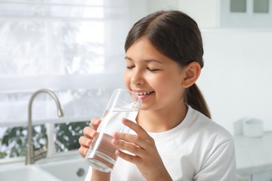Photo of Girl drinking tap water from glass in kitchen