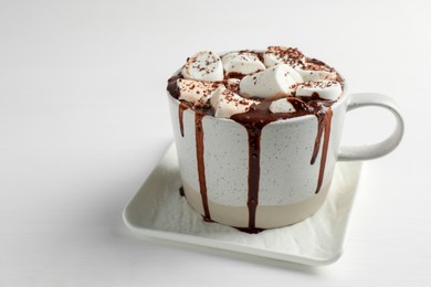 Photo of Delicious hot chocolate with marshmallows and cocoa powder in cup on white table, closeup. Space for text