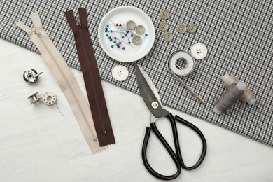 Photo of Flat lay composition with different sewing supplies and fabric on white wooden table