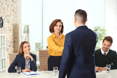 Photo of Human resources manager shaking hands with applicant before job interview in office