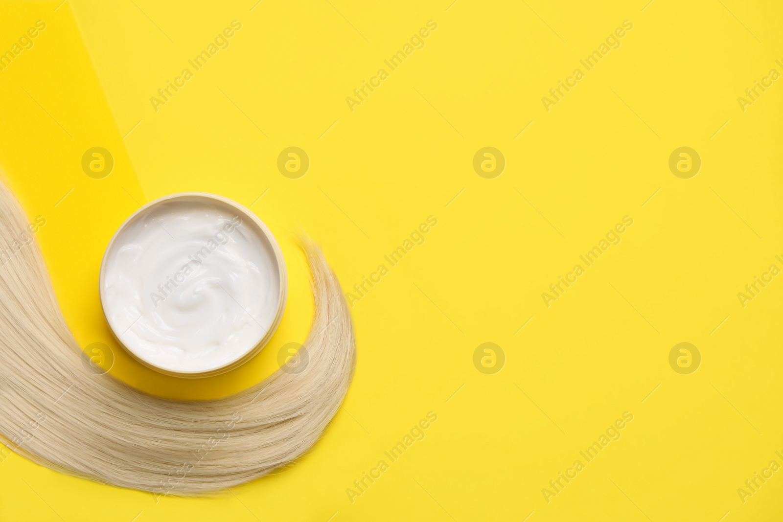 Photo of Lock of healthy blond hair and cosmetic product on yellow background, flat lay. Space for text