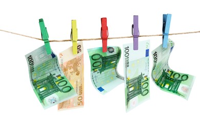 Money laundering. Euro banknotes hanging on clothesline against white background