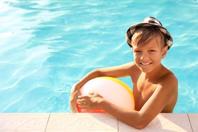 Happy cute boy with inflatable ball in swimming pool