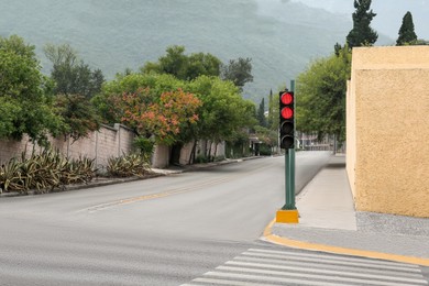 Traffic lights on street near beautiful mountains. Road rules