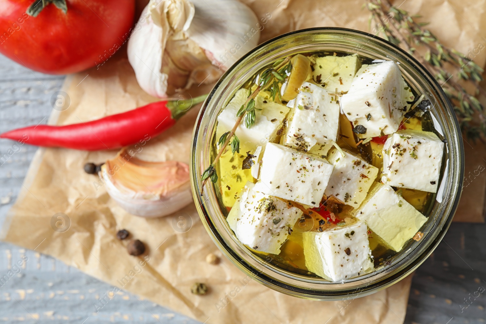 Photo of Composition with pickled feta cheese in jar on grey wooden table, top view