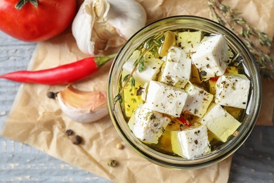 Composition with pickled feta cheese in jar on grey wooden table, top view