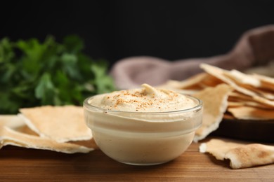 Photo of Delicious hummus with pita chips on wooden table