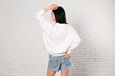 Photo of Young woman in sweater at brick wall. Mock up for design