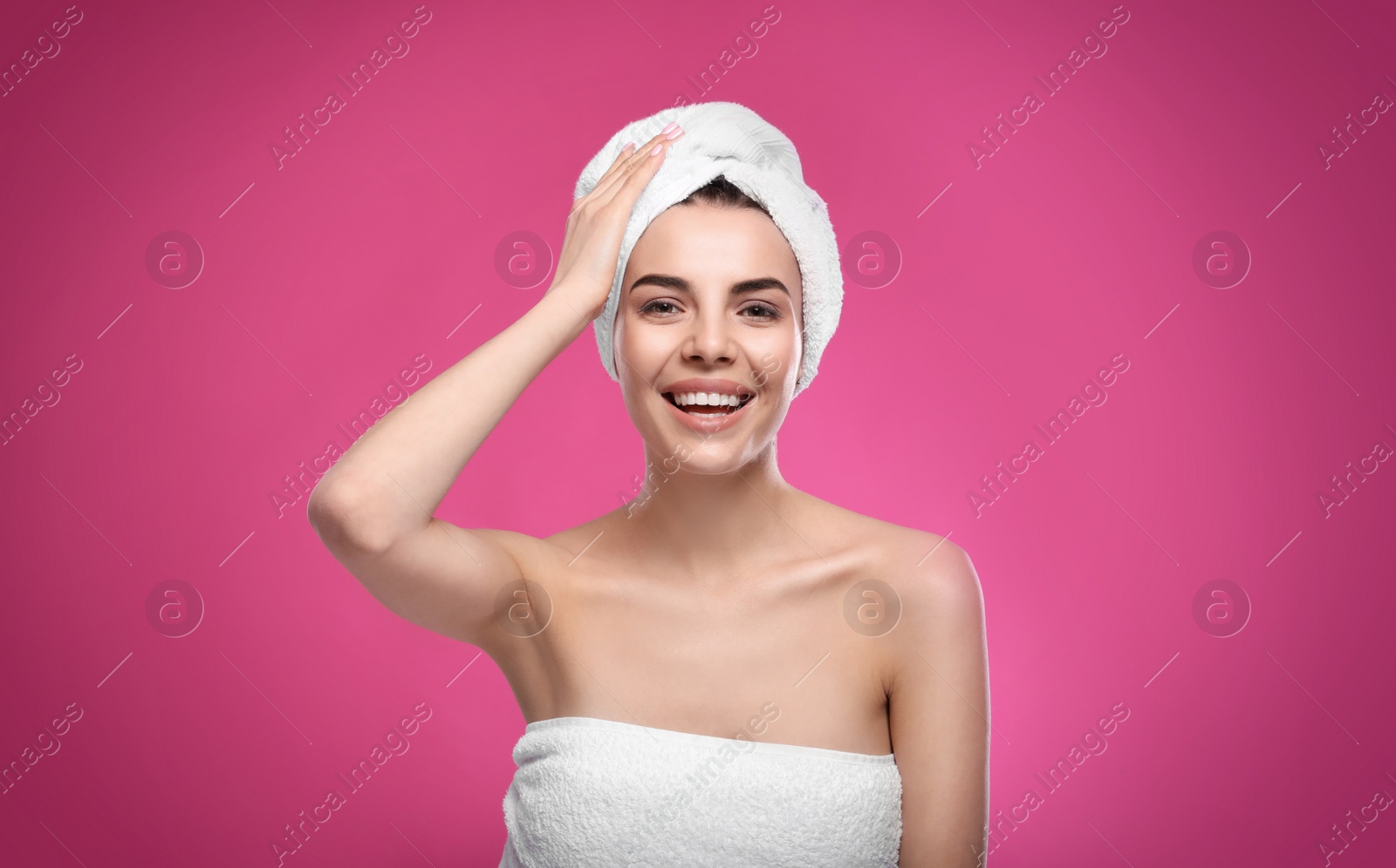 Photo of Happy young woman with towel on head against pink background. Washing hair