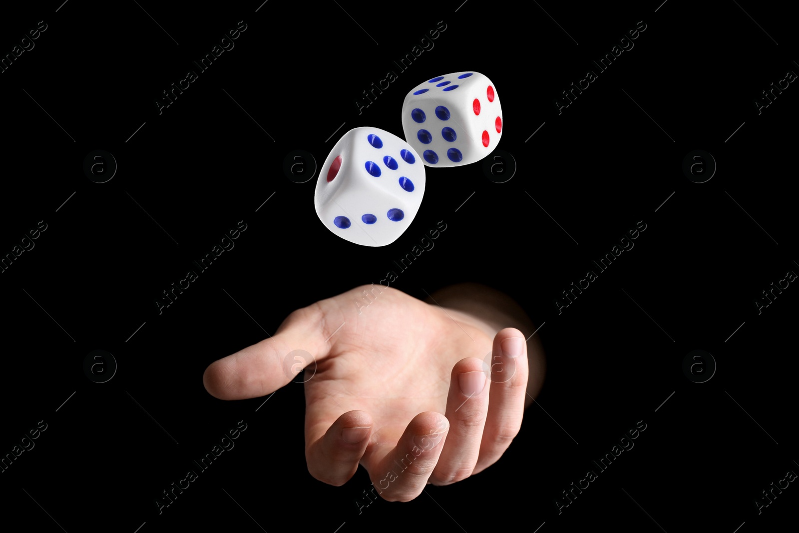 Image of Man throwing white dice on black background, closeup