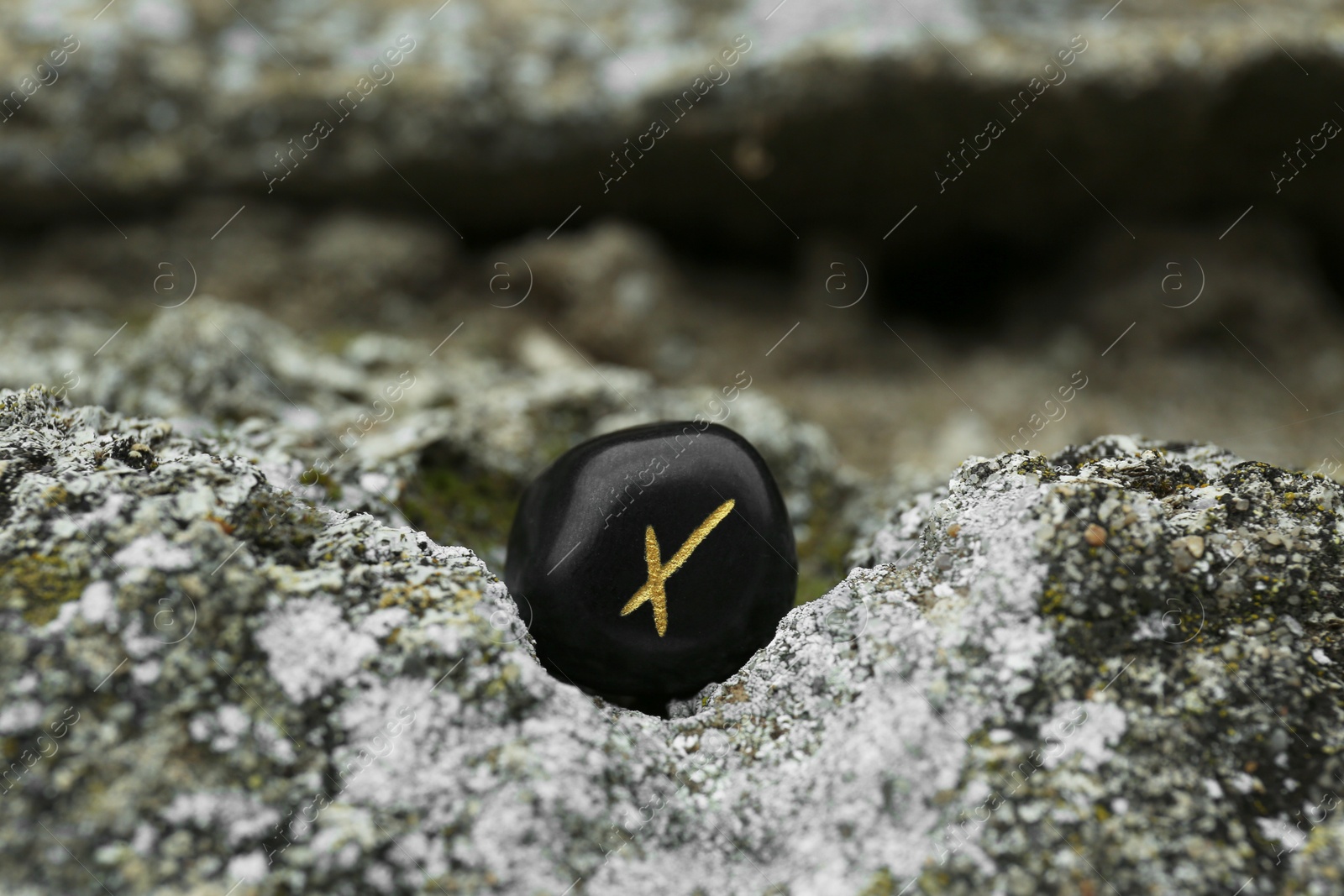 Photo of Black rune Nauthiz on stone outdoors, closeup