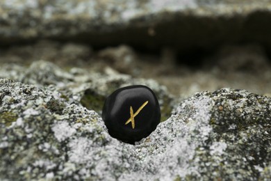 Photo of Black rune Nauthiz on stone outdoors, closeup