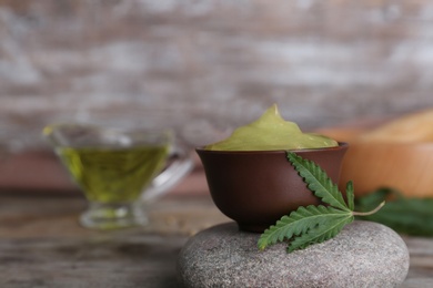 Photo of Bowl of hemp lotion on wooden table