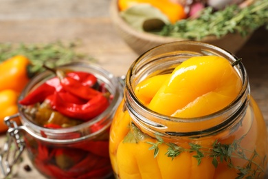 Photo of Glass jars with pickled peppers on table, closeup
