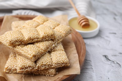 Wooden tray with delicious sweet kozinaki bars and honey on white textured table, closeup. Space for text