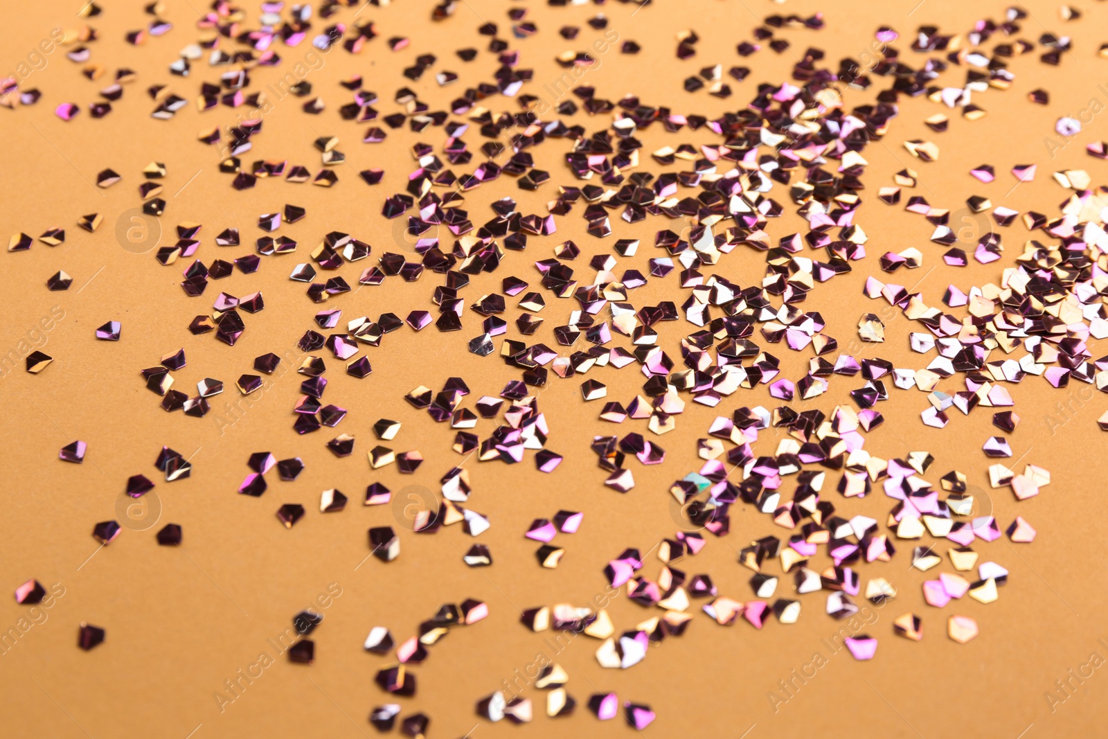 Photo of Shiny bright glitter on beige background, closeup