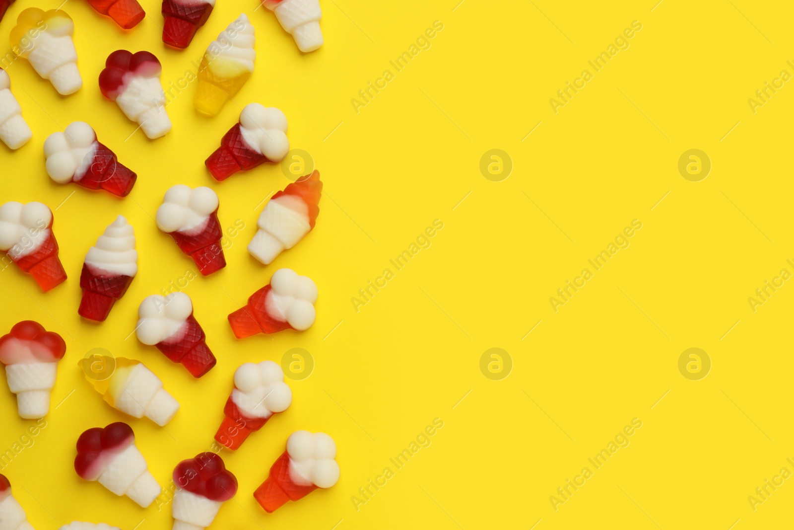 Photo of Tasty jelly candies in shape of ice cream on yellow background, flat lay. Space for text