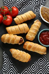 Photo of Delicious sausage rolls and ingredients on grey table, flat lay