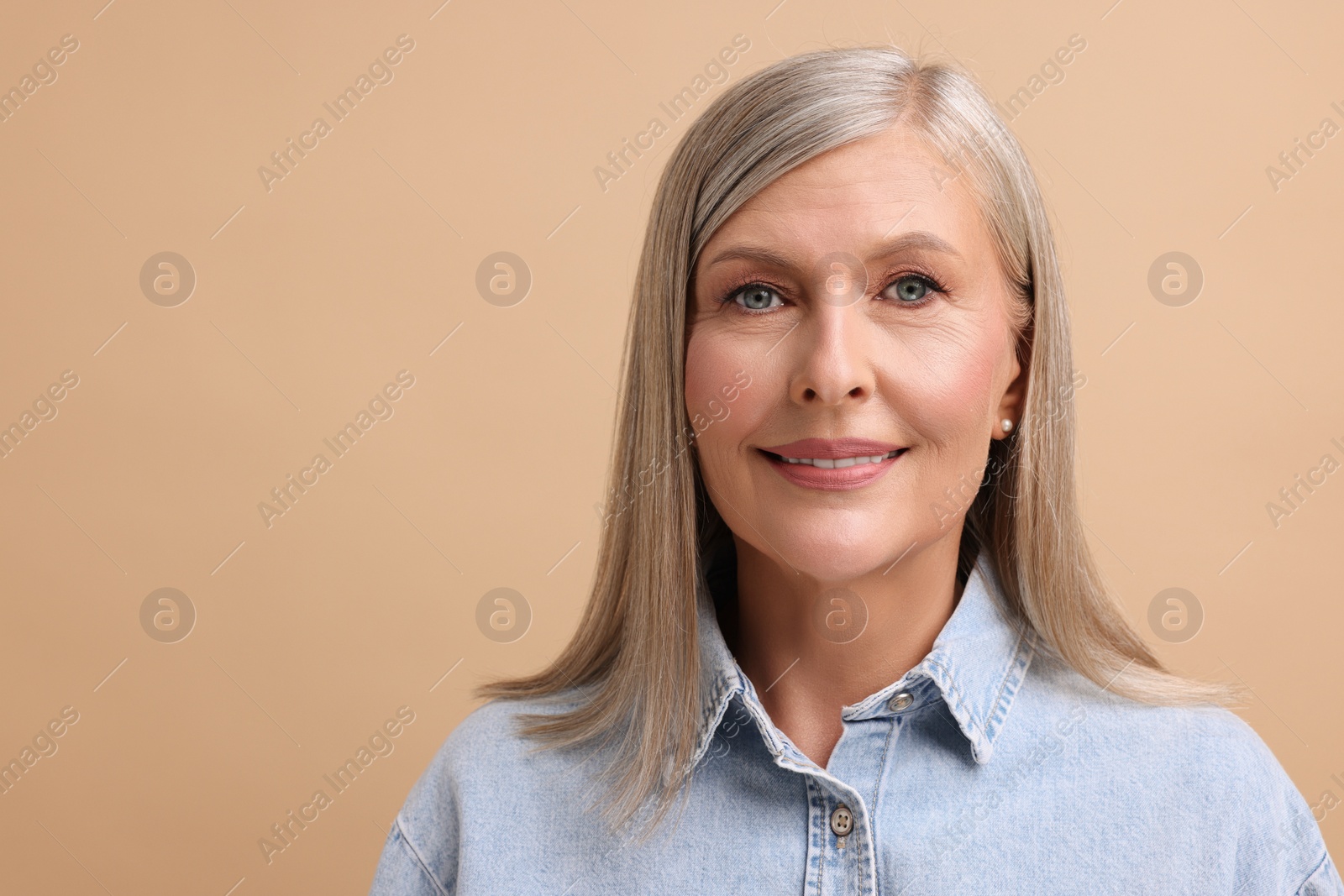 Photo of Portrait of beautiful middle aged woman on beige background. Space for text