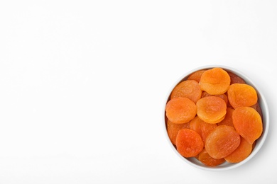 Photo of Bowl of dried apricots on white background, top view with space for text. Healthy fruit