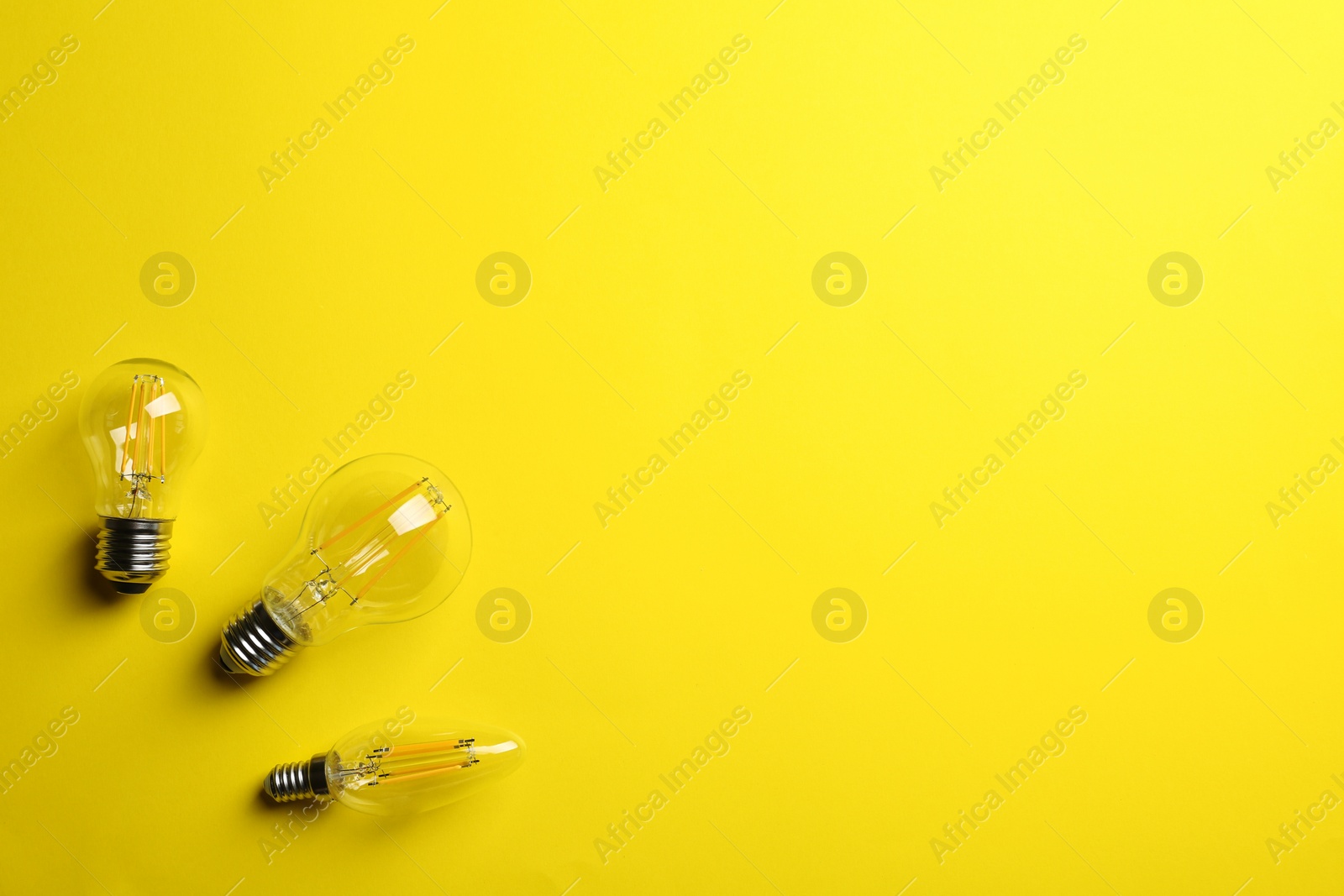 Photo of Vintage lamp bulbs on yellow background, top view. Space for text