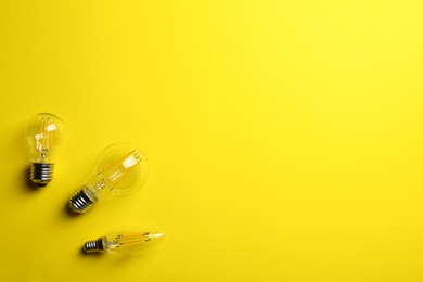 Photo of Vintage lamp bulbs on yellow background, top view. Space for text