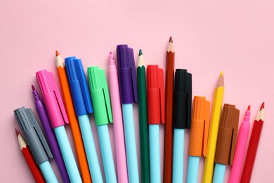Photo of Different colorful pencils and felt tip pens on pink background, flat lay. Diversity concept