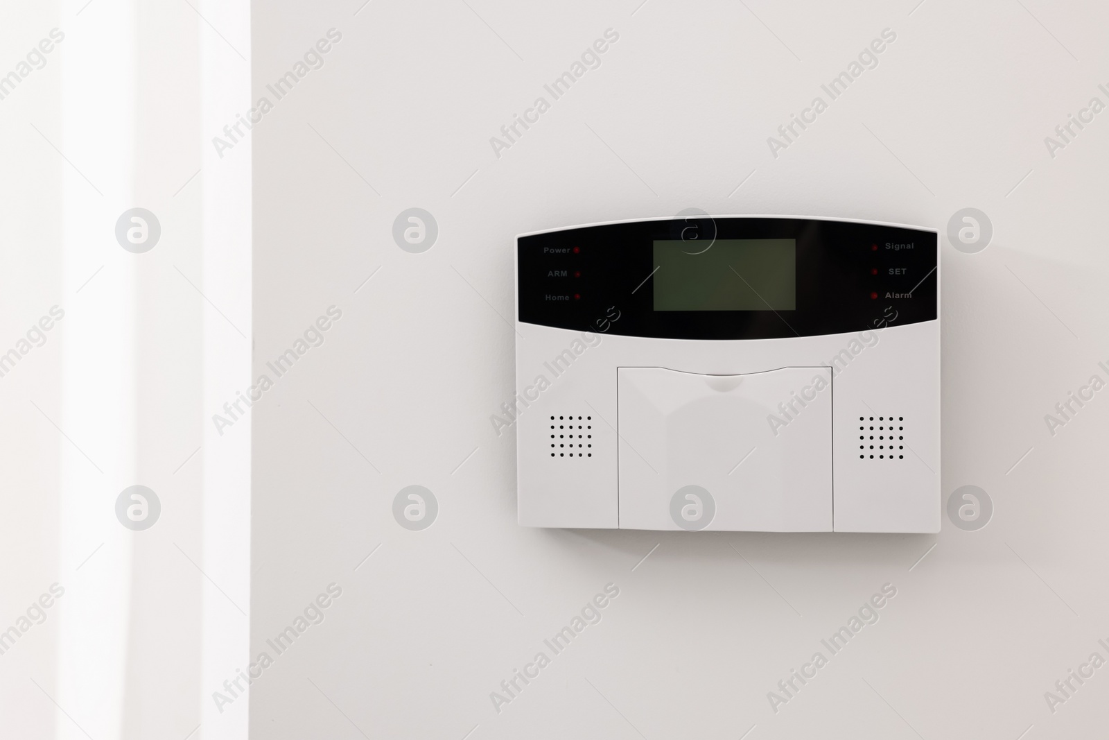 Photo of Home security alarm system on white wall indoors, space for text