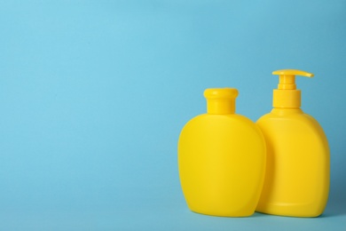 Photo of Bottles with hair care cosmetics on light blue background