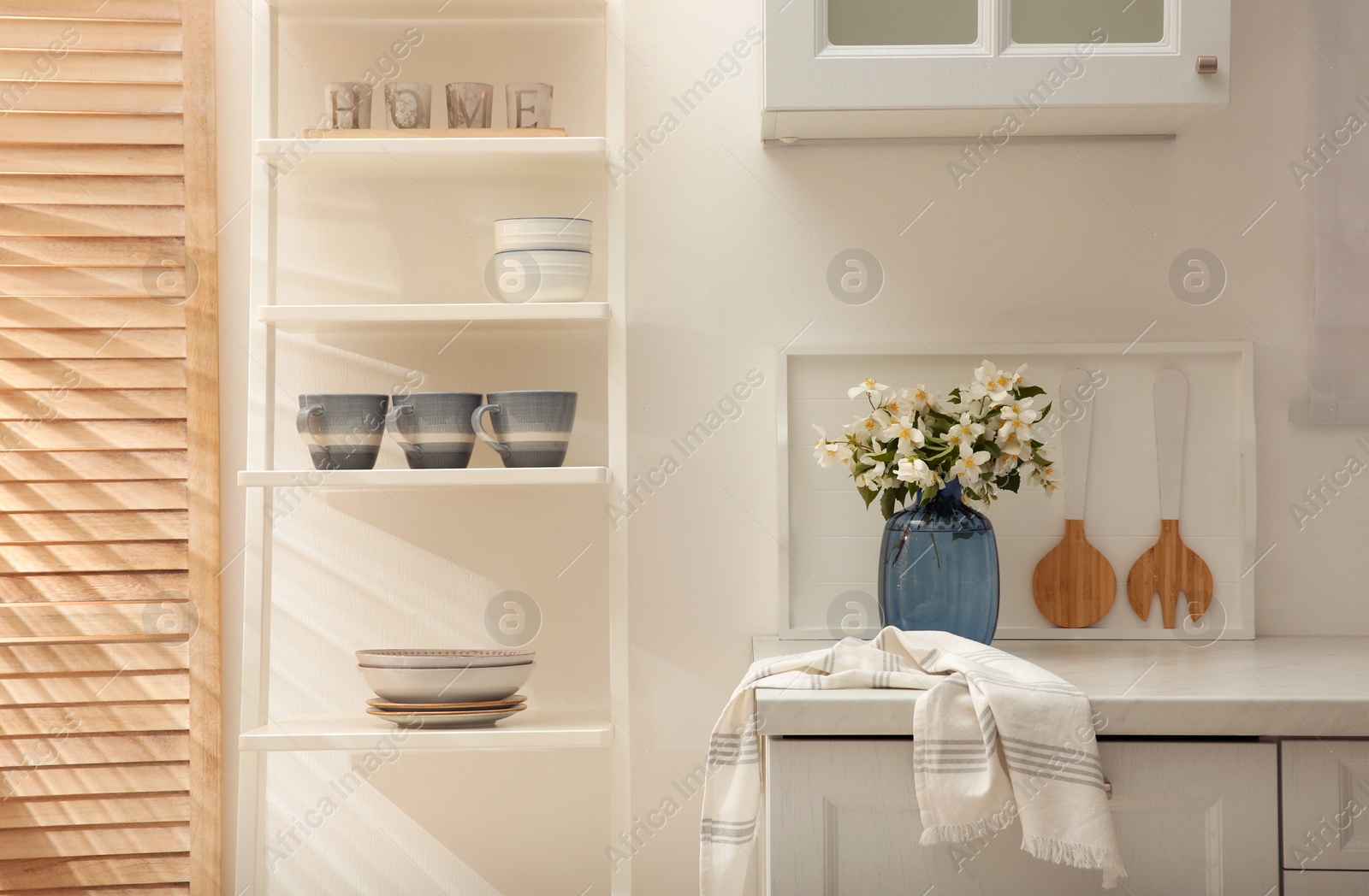 Photo of Vase with beautiful jasmine flowers on countertop in kitchen