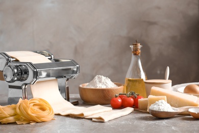 Pasta maker with dough and products on kitchen table