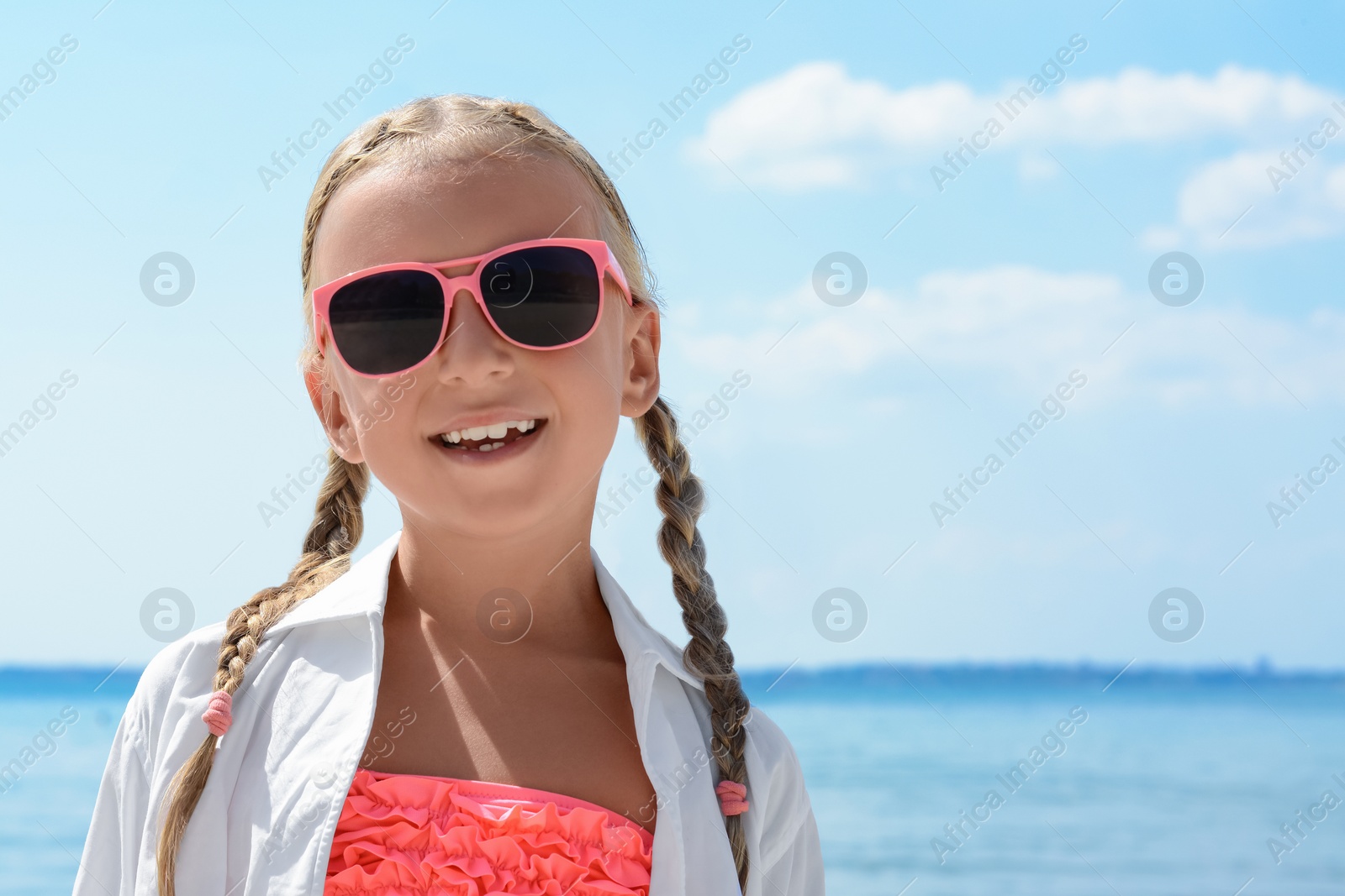 Photo of Little girl wearing sunglasses at beach on sunny day. Space for text