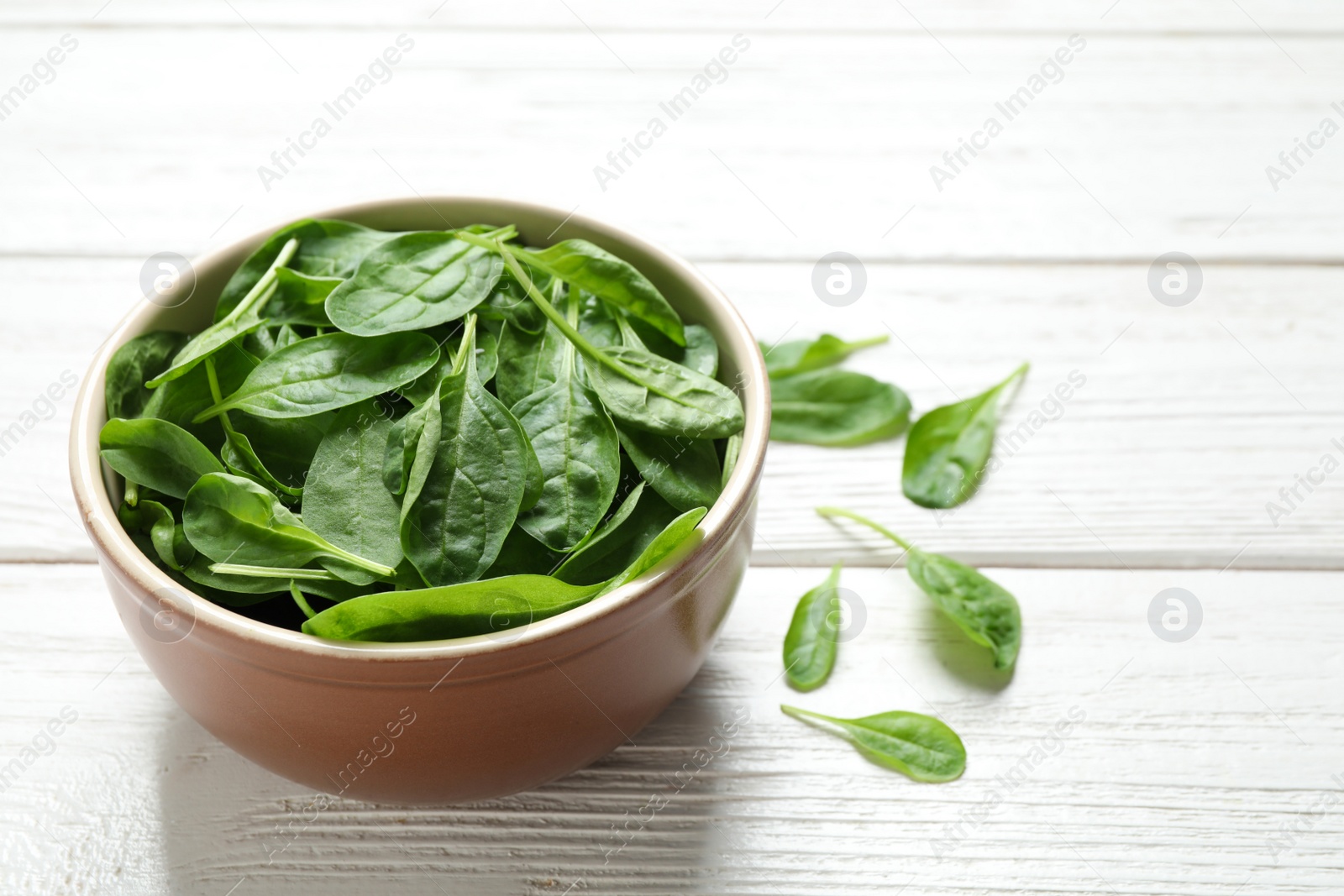 Photo of Fresh green healthy spinach on white wooden table. Space for text