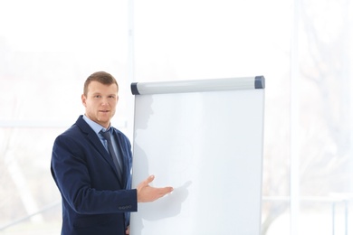 Business trainer giving presentation on flip chart board indoors