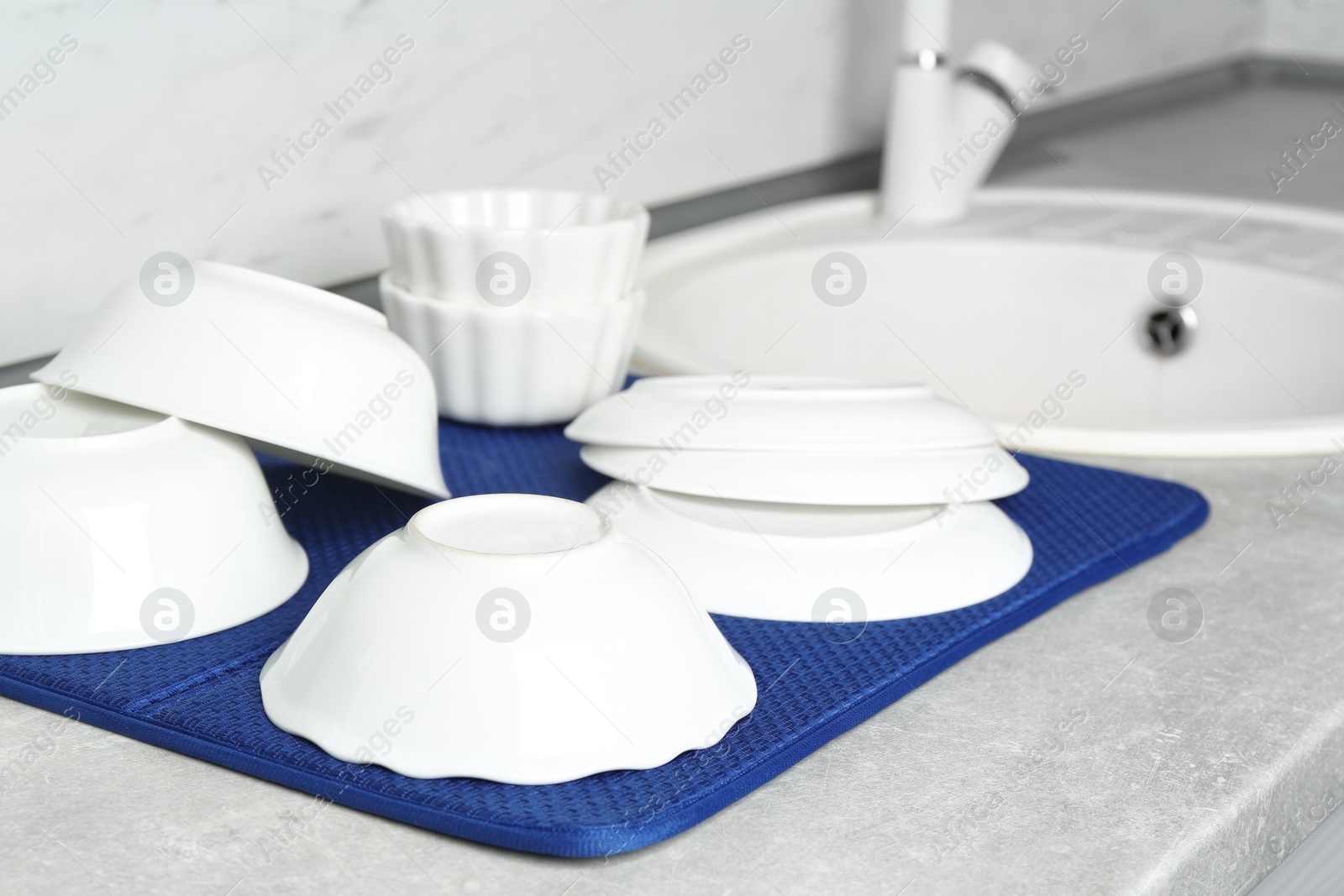 Photo of Different clean plates near sink on kitchen counter