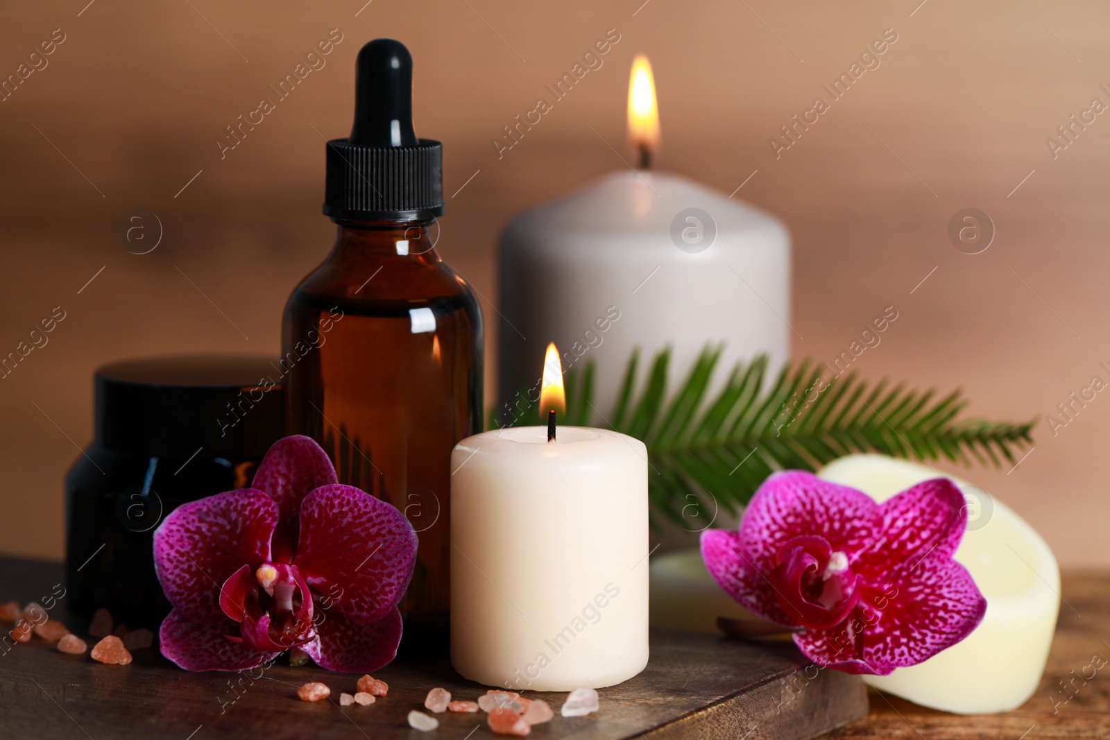 Photo of Beautiful spa composition with different care products and burning candles on wooden table