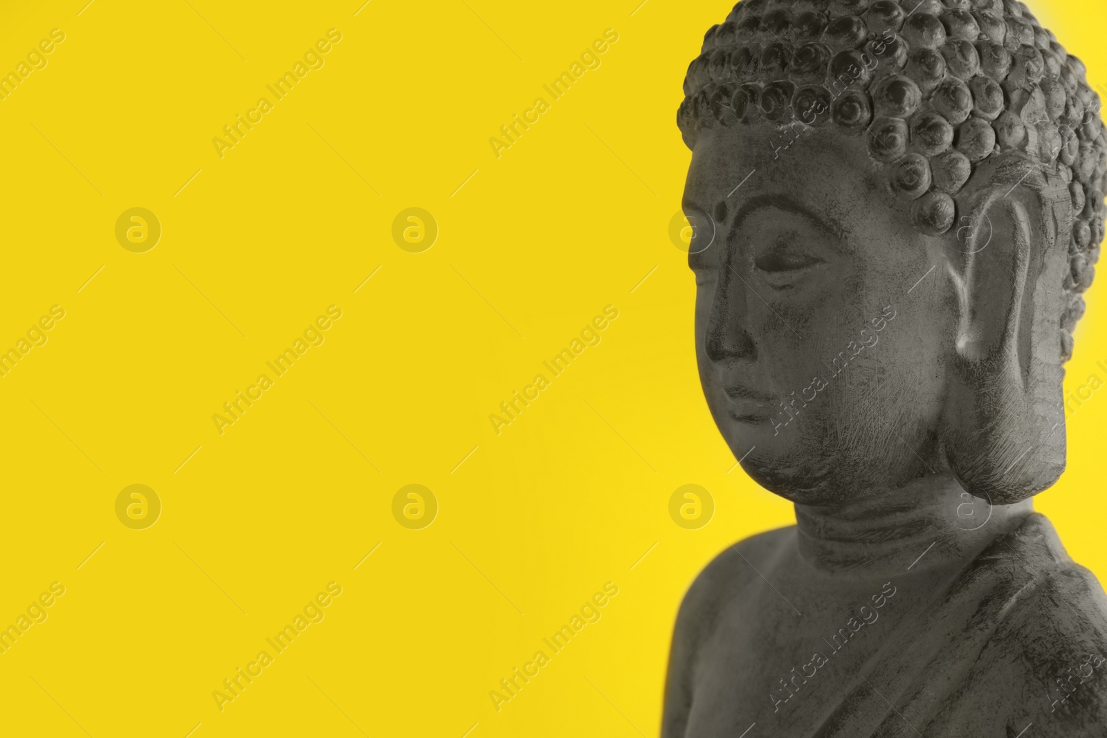 Photo of Beautiful stone Buddha sculpture on yellow background. Space for text